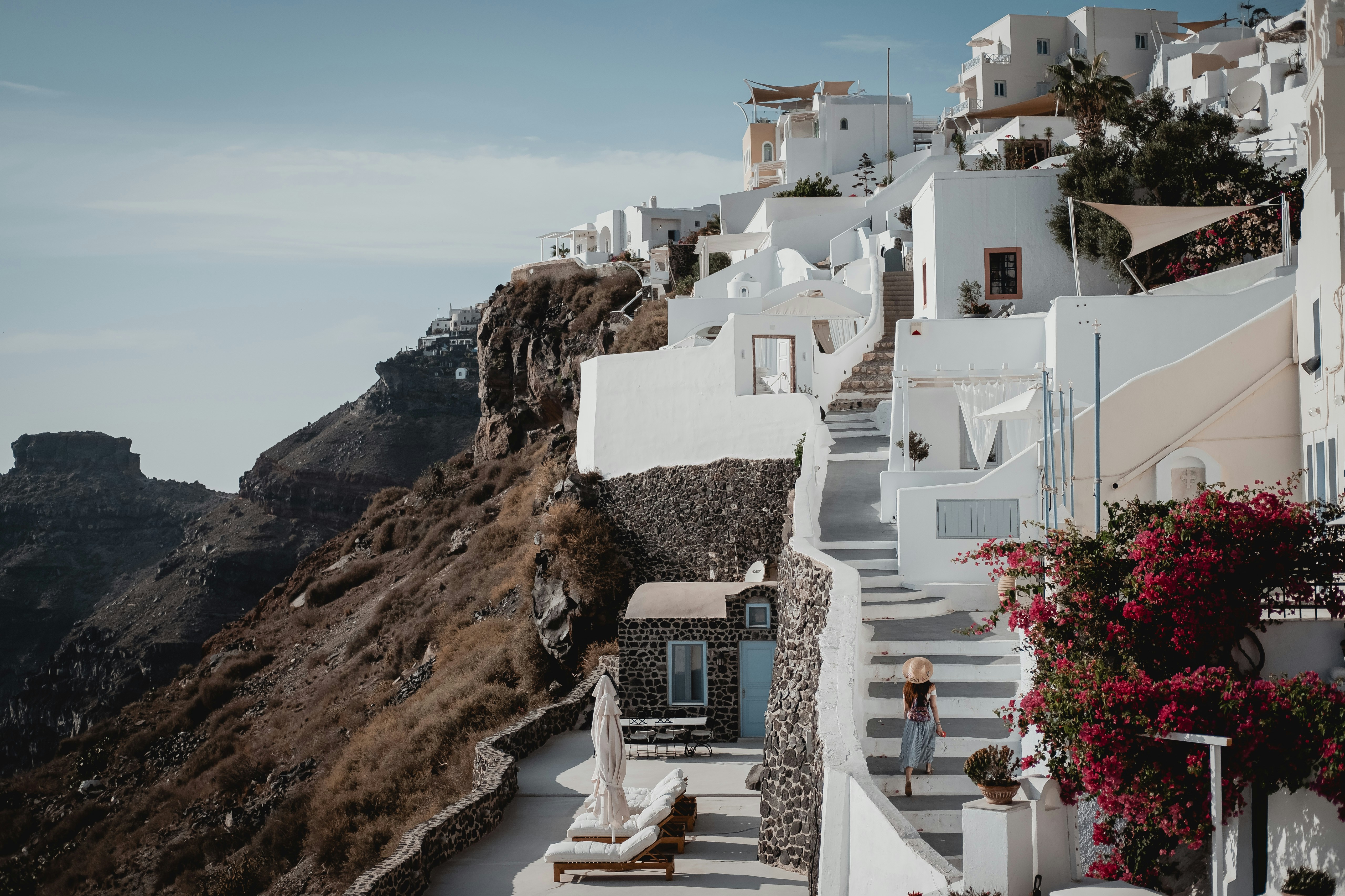 white concrete building on brown rock formation near body of water during daytime, Santorini steps. www.febiyan.com