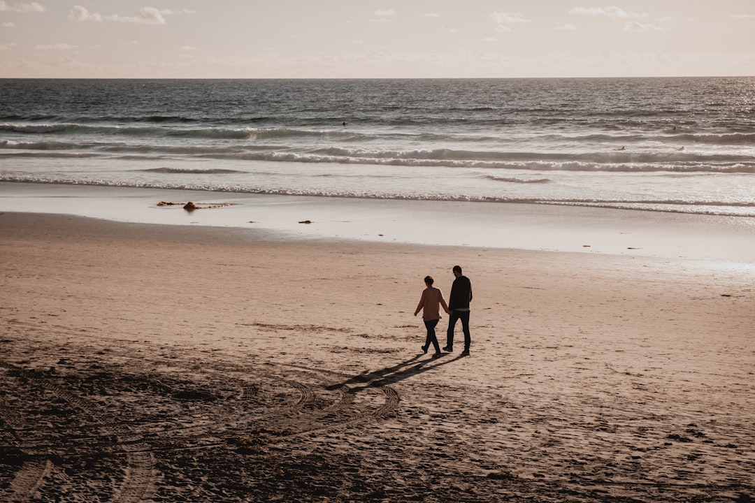 2 boys walking on beach during daytime