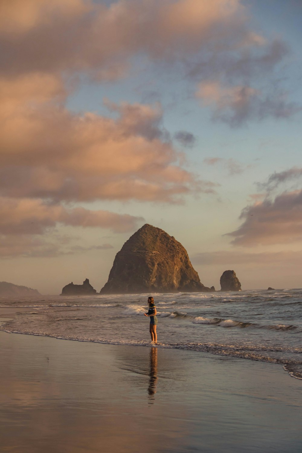 person in red shirt standing on beach during sunset