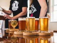 Visitors enjoying a guided tasting session with glasses of different beer styles on a rustic wooden table.