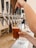 A hand is pulling a tap handle on a row of beer taps, filling a glass with amber-colored beer. The setting appears to be a bar or a brewery with a countertop in the foreground.