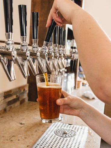 Technician repairing a beer tap machine with tools on a bright workbench.