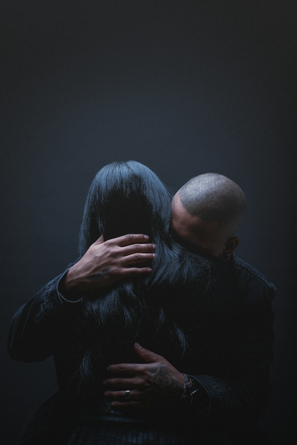 hombre con camisa de vestir negra abrazando a mujer con camisa negra de manga larga