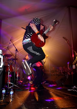man in black and white long sleeve shirt playing guitar on stage