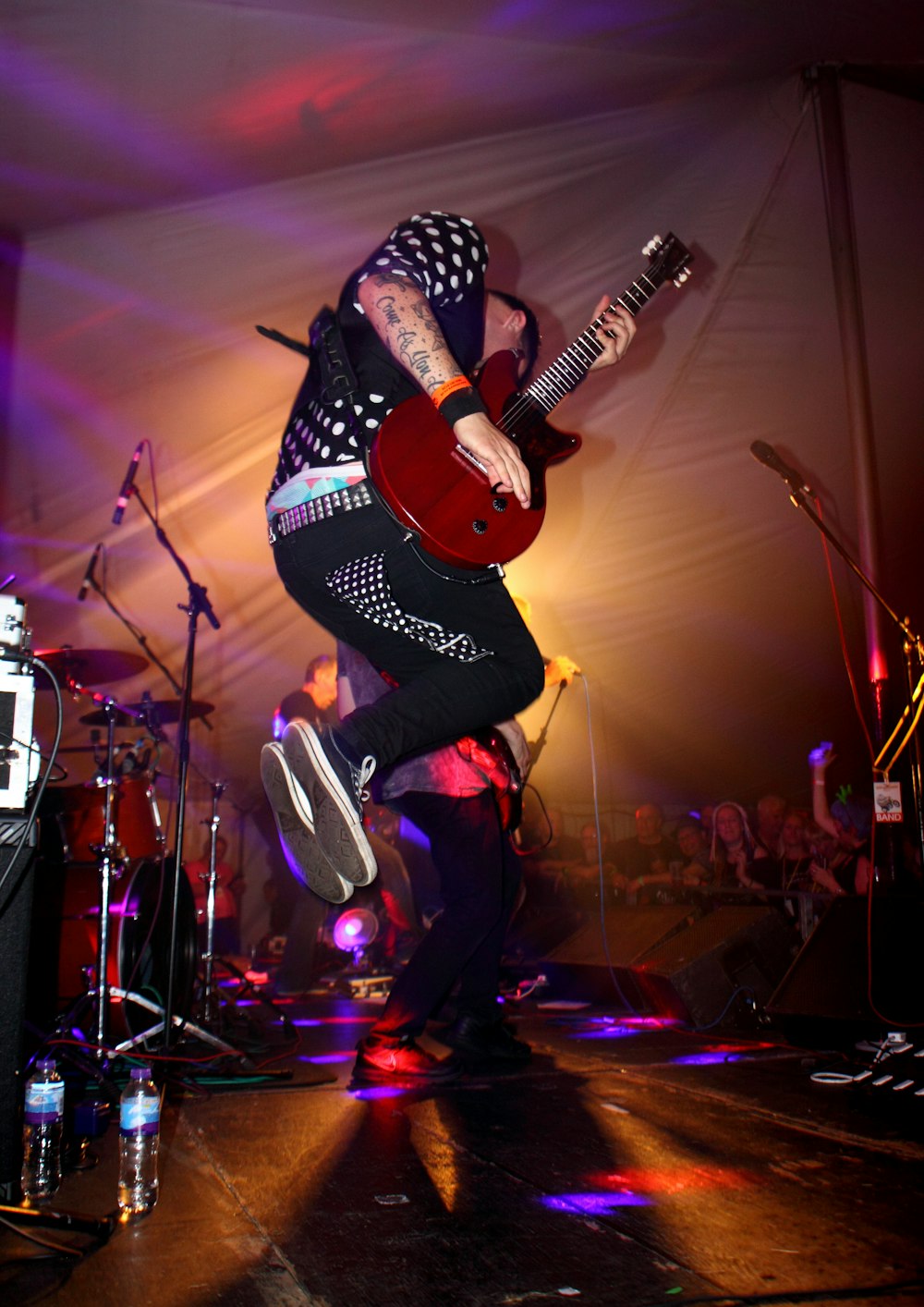 man in black and white long sleeve shirt playing guitar on stage