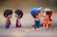 Two pairs of small figurines depicting young couples facing each other. The background is softly blurred to enhance the focus on the figurines. One pair stands facing each other, while the other pair is sitting, creating a warm, playful atmosphere.