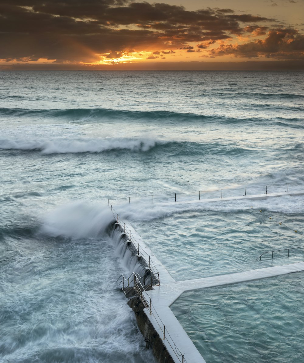 olas del océano rompiendo en la playa durante la puesta del sol