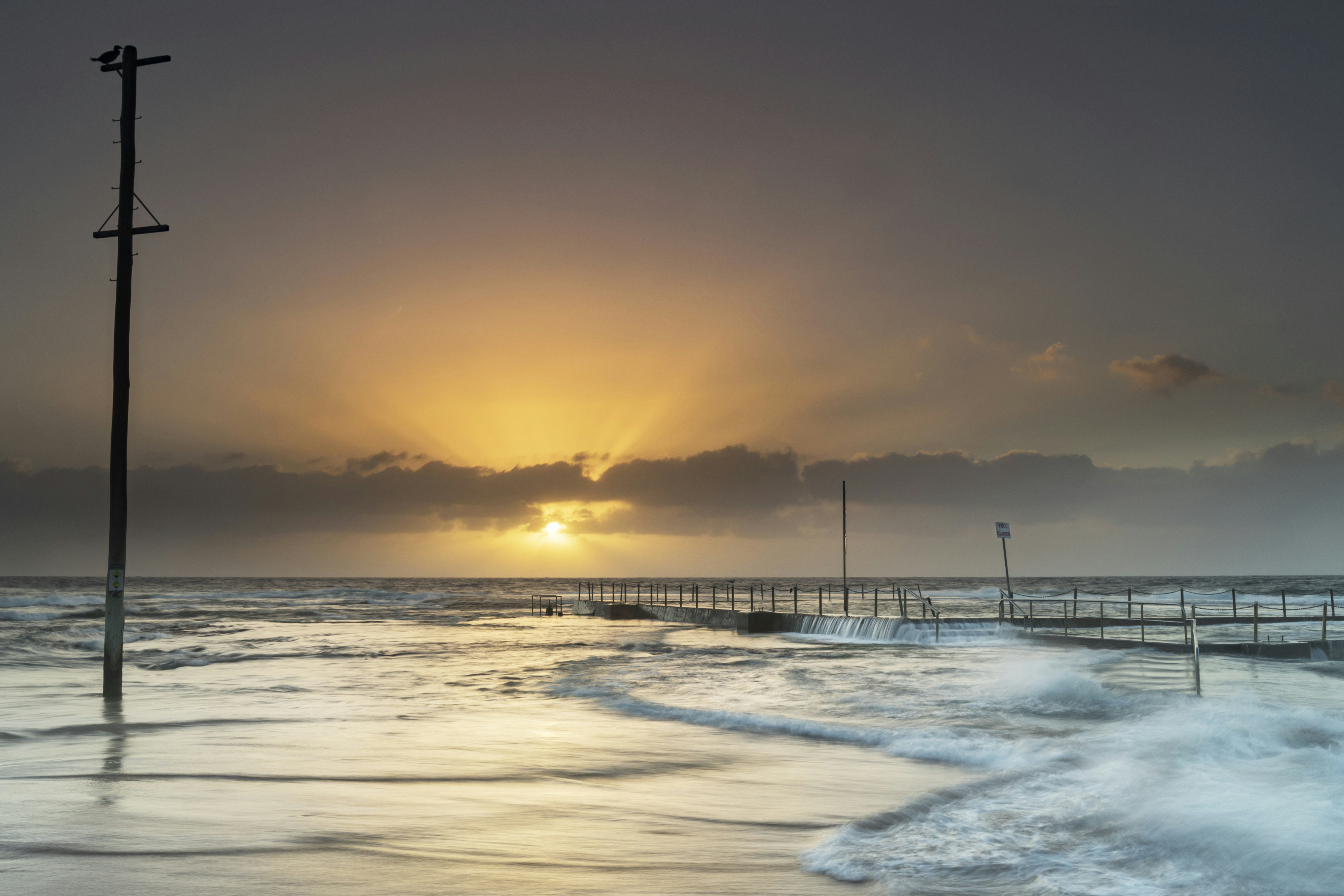 sea waves crashing on shore during sunset