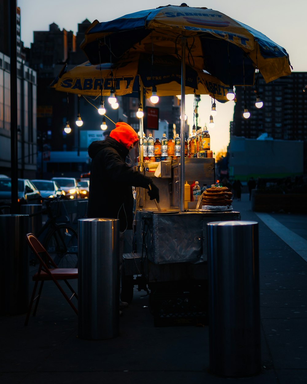 person in red hoodie standing near food stall during night time
