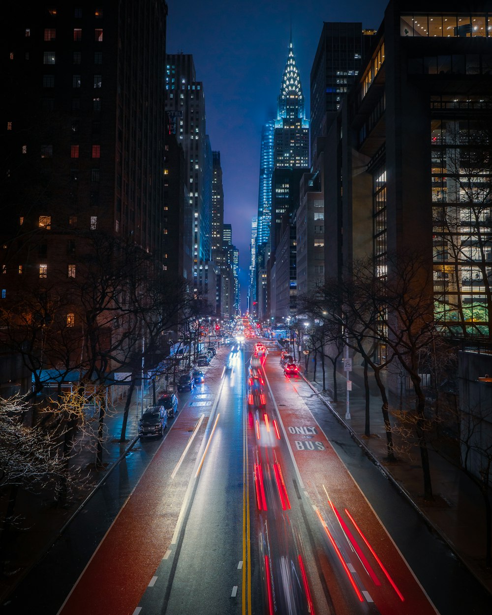 Photographie en accéléré de voitures sur la route entre des immeubles de grande hauteur pendant la nuit