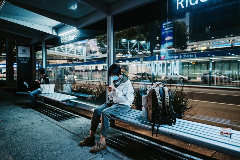 a man sitting on a bench looking at his cell phone