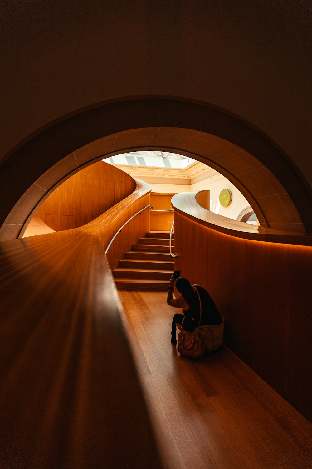 man in black jacket sitting on brown wooden staircase