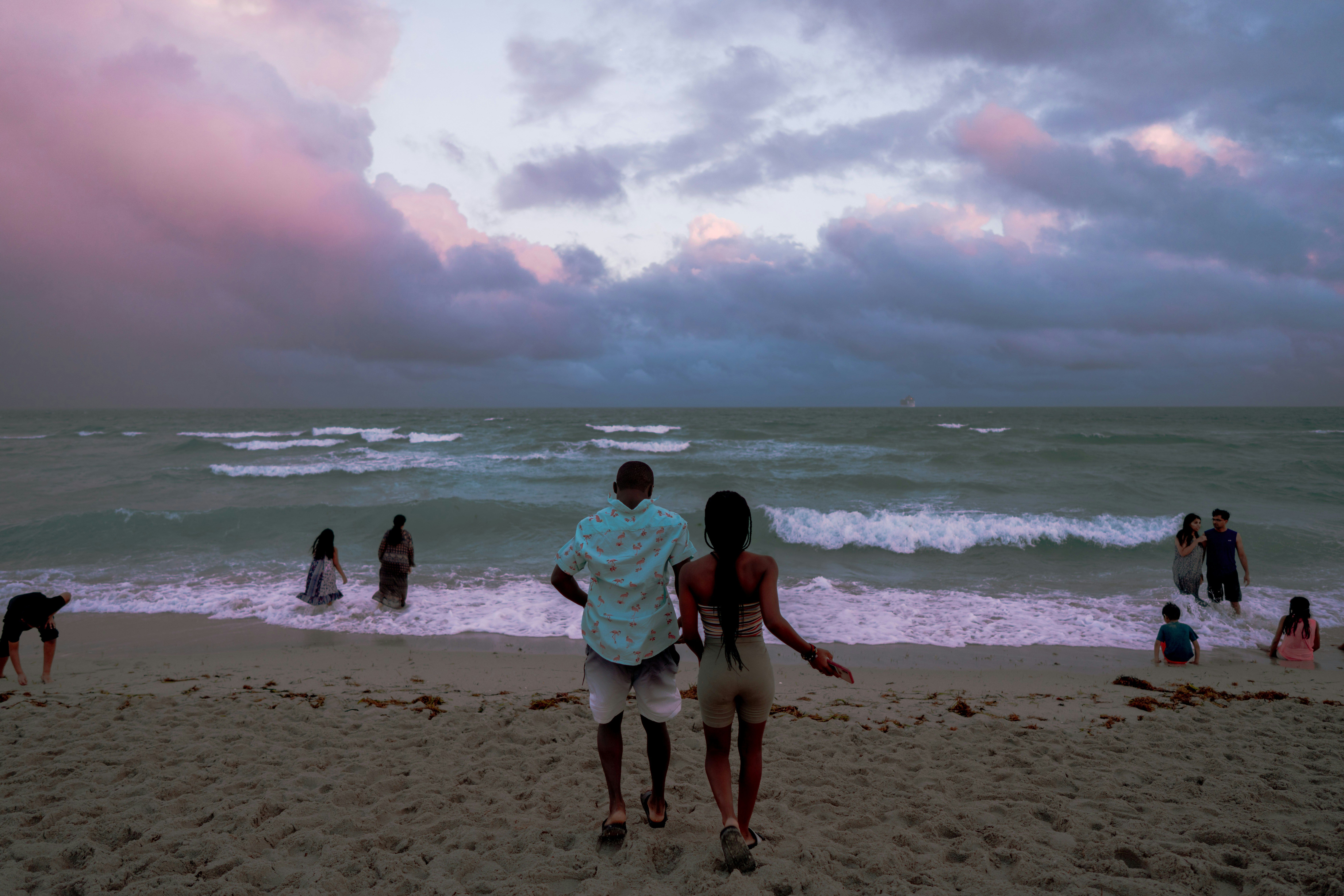 man and woman walking on beach during daytime