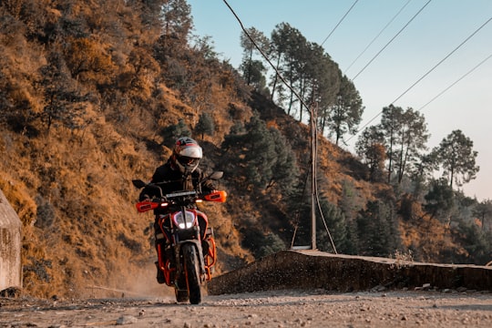 man in black helmet riding red motorcycle on road during daytime in Dharamshala India