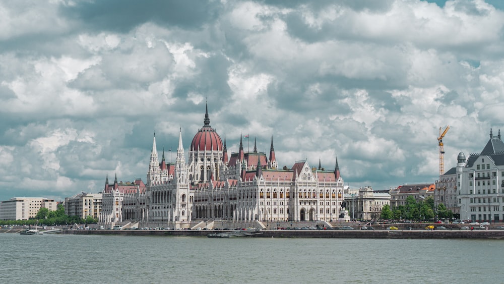 Weiß-rotes Betongebäude in der Nähe von Gewässern unter bewölktem Himmel tagsüber