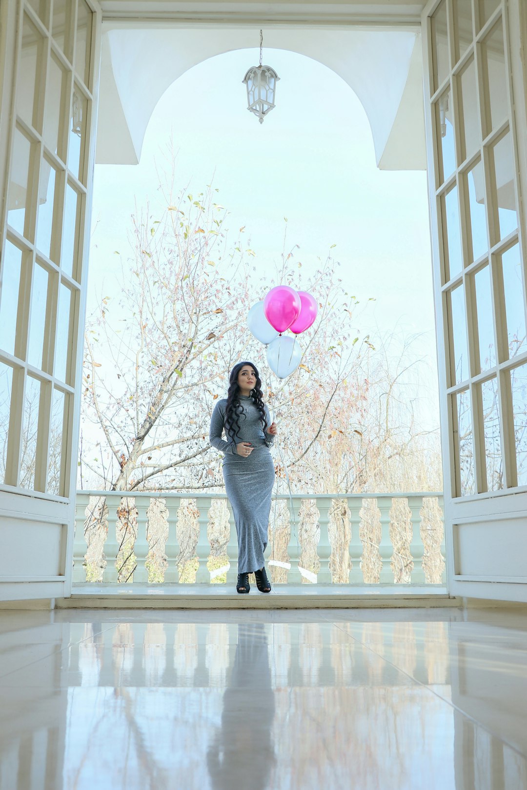 woman in black jacket and blue denim jeans holding pink balloons