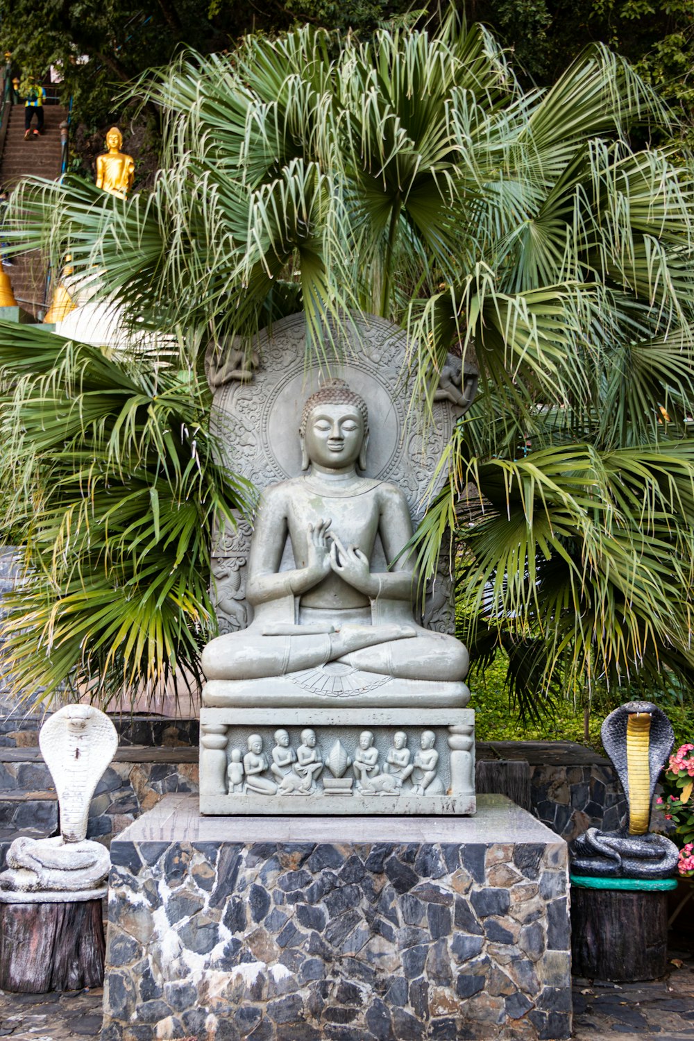 gray concrete statue near palm trees during daytime