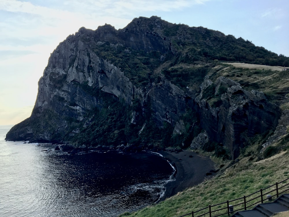 gray rocky mountain beside body of water during daytime