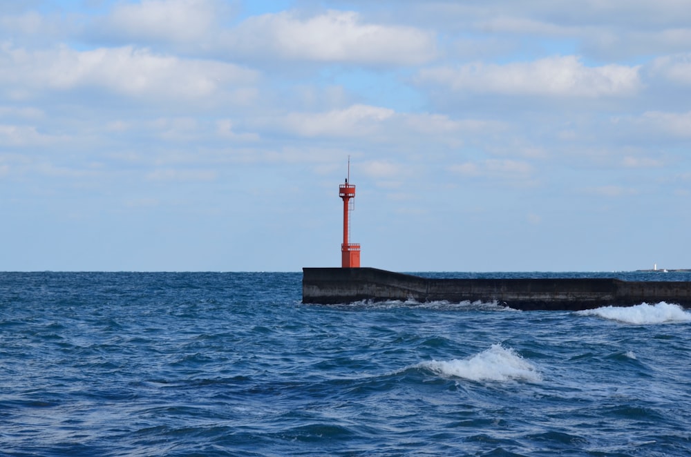 farol vermelho e branco no mar durante o dia