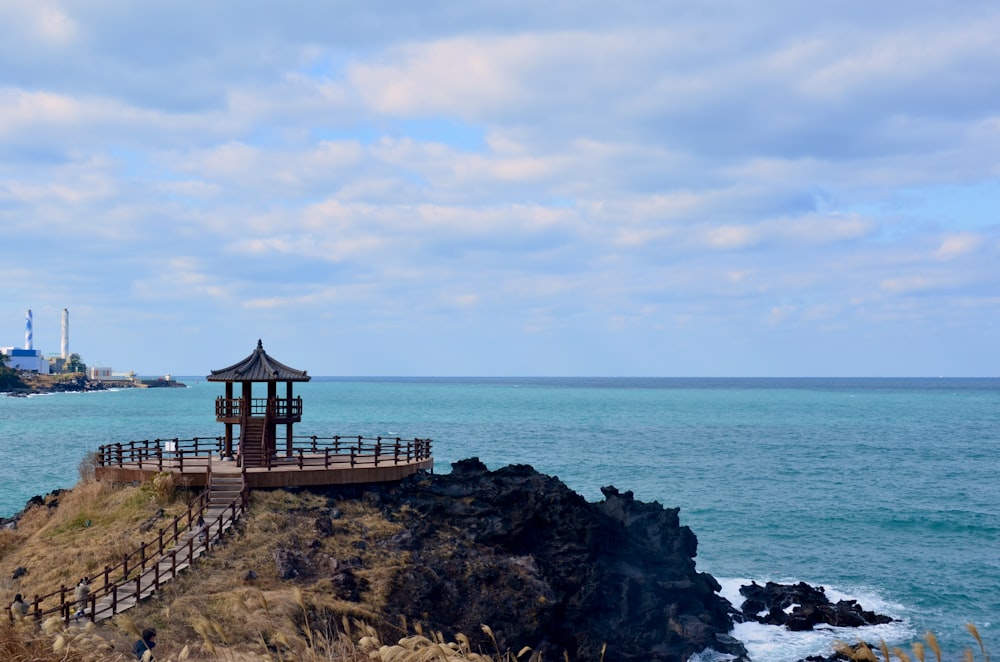 a gazebo sitting on top of a cliff next to the ocean