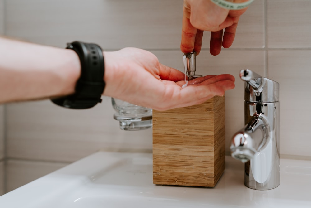 person holding silver faucet in sink