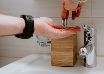 person holding silver faucet in sink