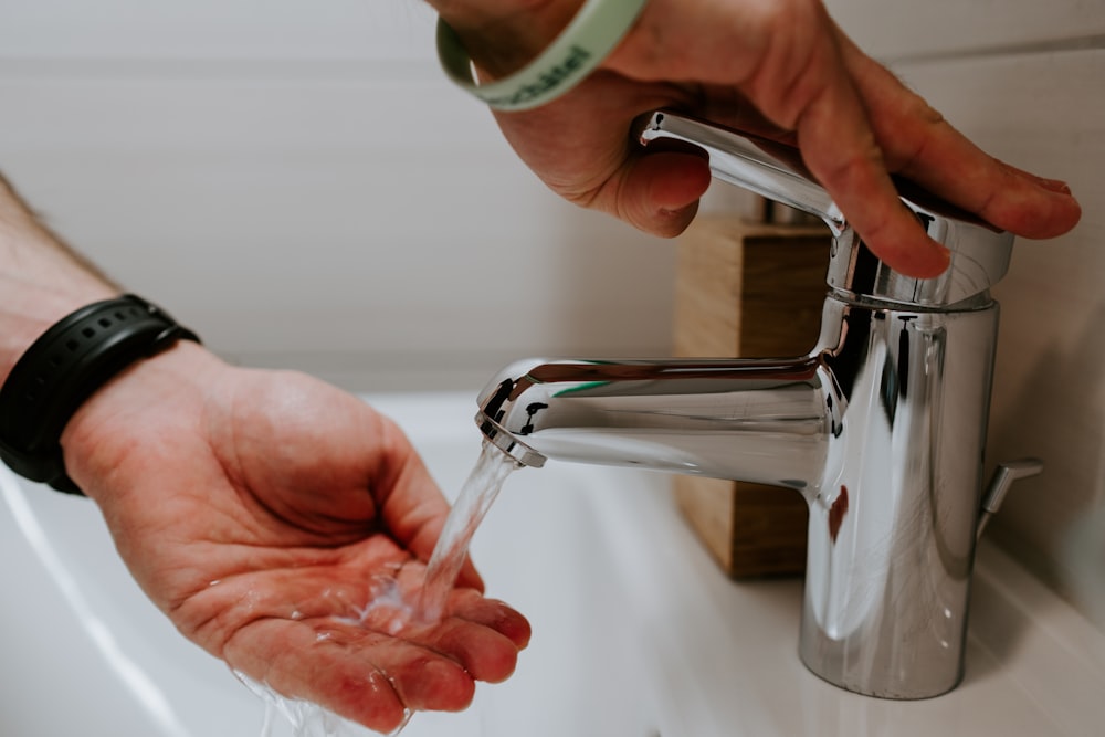 person holding stainless steel faucet