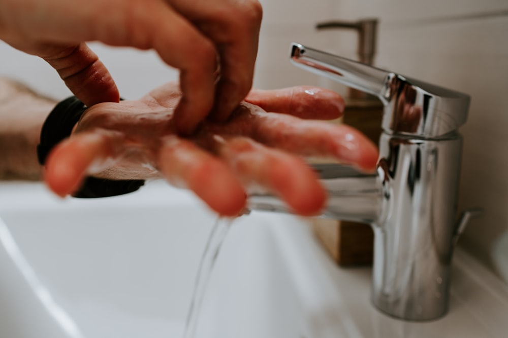 person holding stainless steel faucet