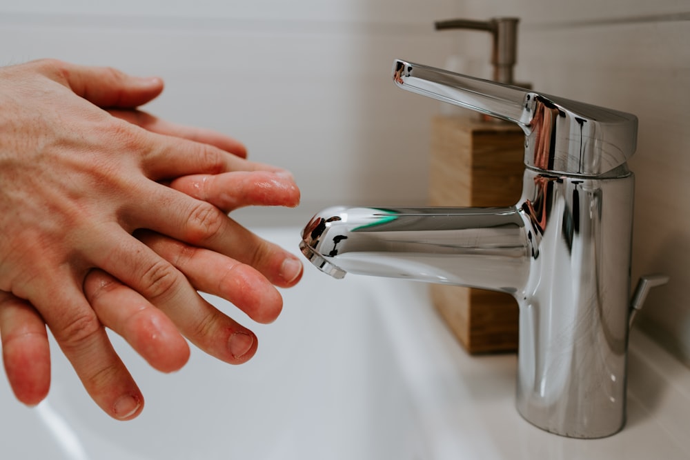 person holding stainless steel faucet