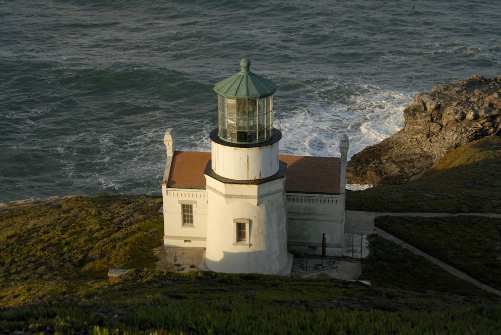 white concrete lighthouse near body of water during daytime