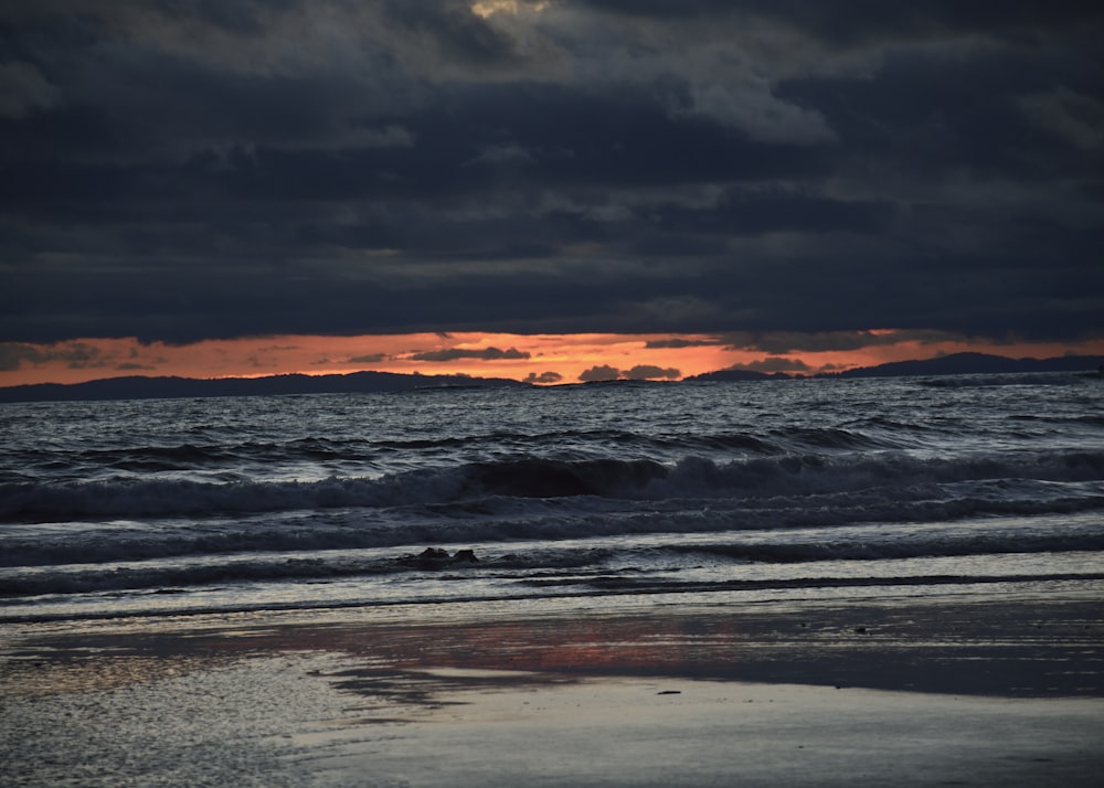 ocean waves crashing on shore during sunset