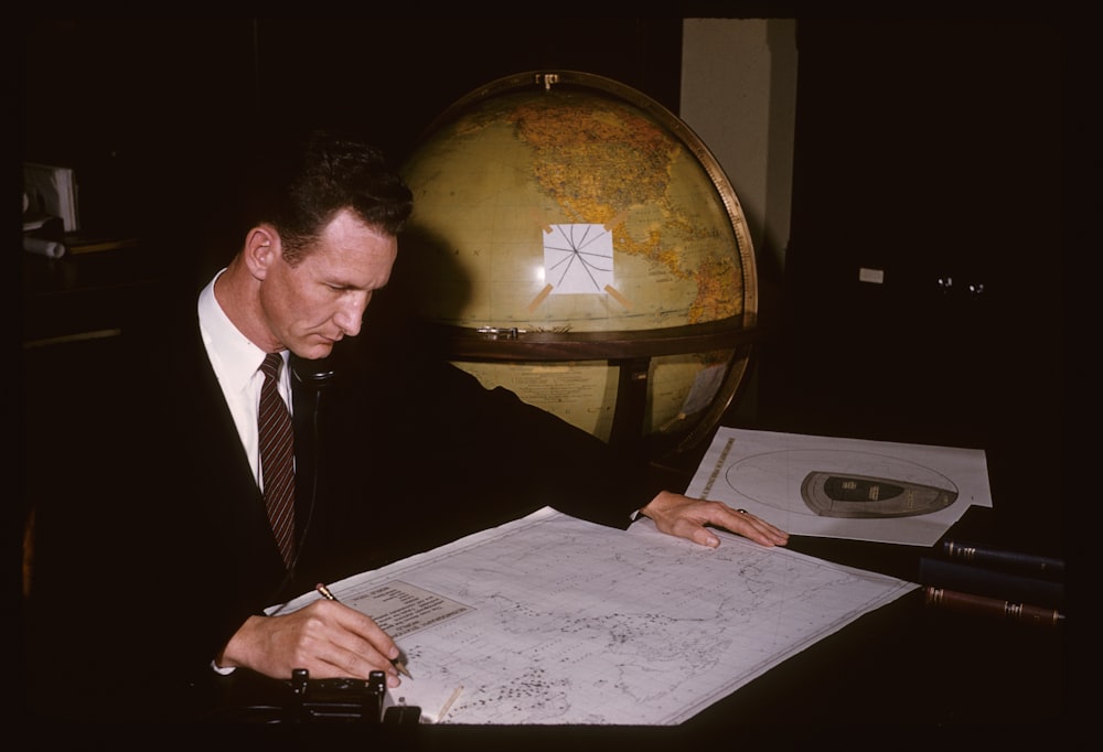 man in black suit jacket writing on white paper