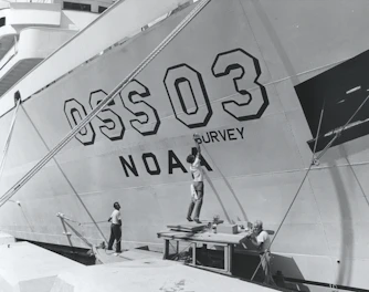 man in white shirt and blue denim jeans standing on white ship
