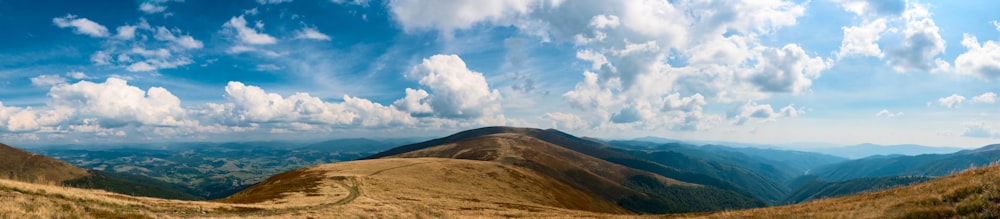 brown mountain under white clouds and blue sky during daytime