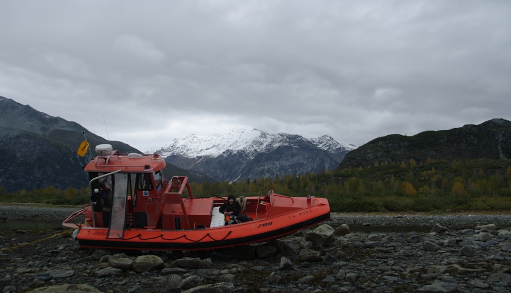 red boat on body of water near mountain during daytime