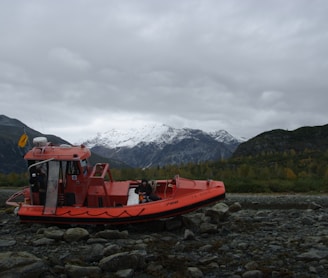 red boat on body of water near mountain during daytime