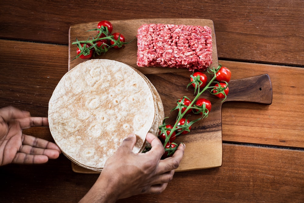 person holding red rose beside brown wooden round table