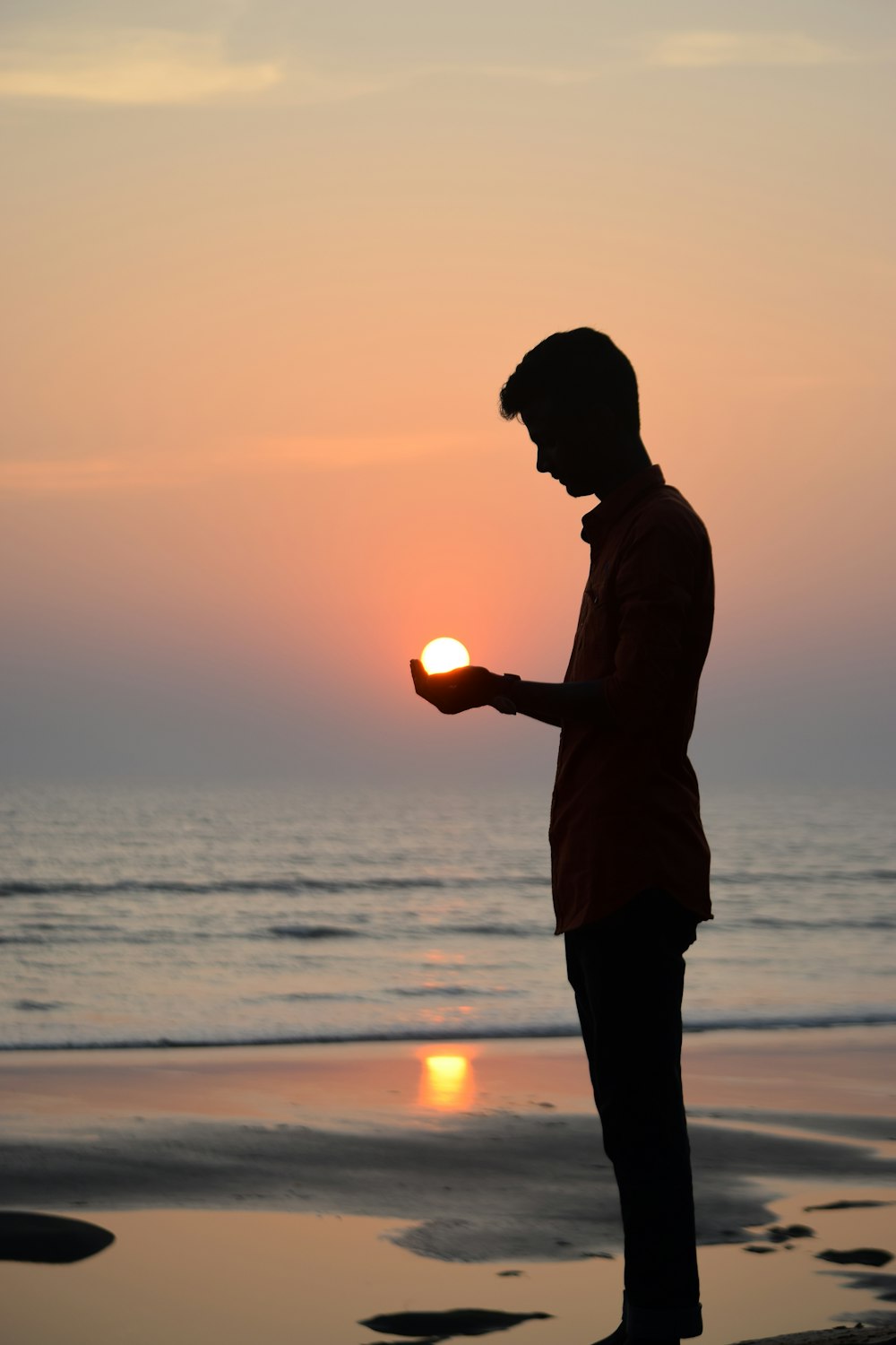 silhouette dell'uomo in piedi sulla riva del mare durante il tramonto