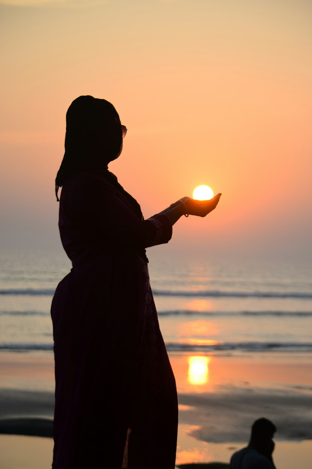 silhouette of woman standing on beach during sunset