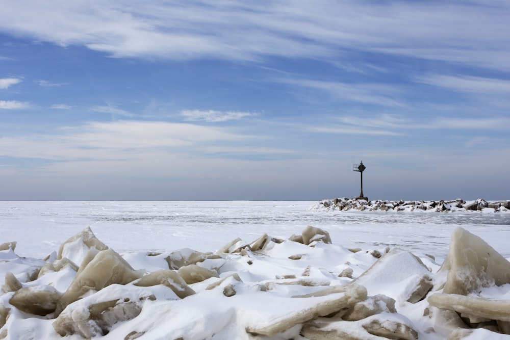 Persona de pie en roca blanca cerca del mar bajo el cielo azul durante el día