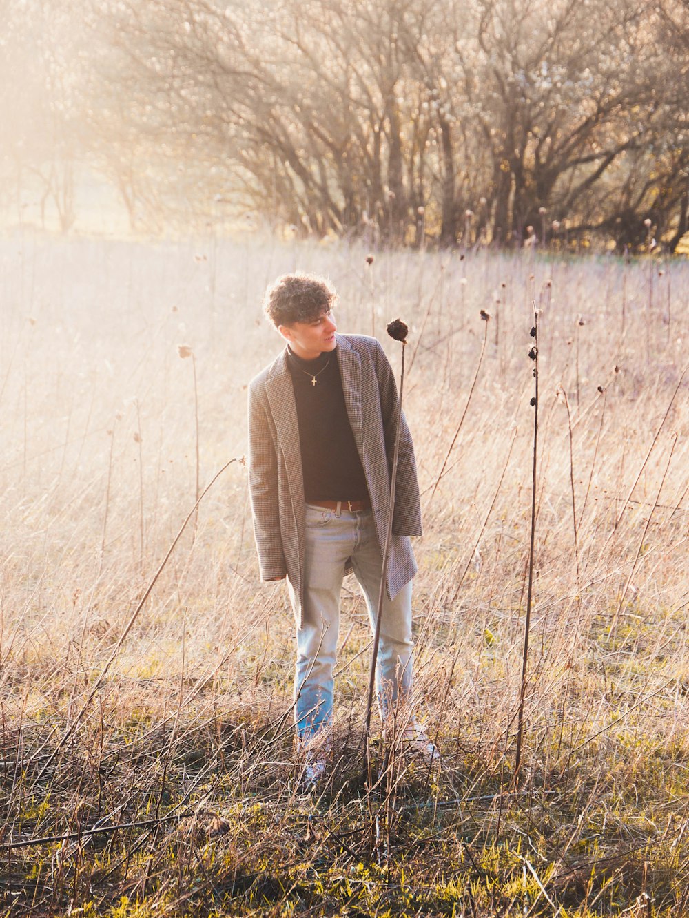 man in brown coat walking on grass field during daytime