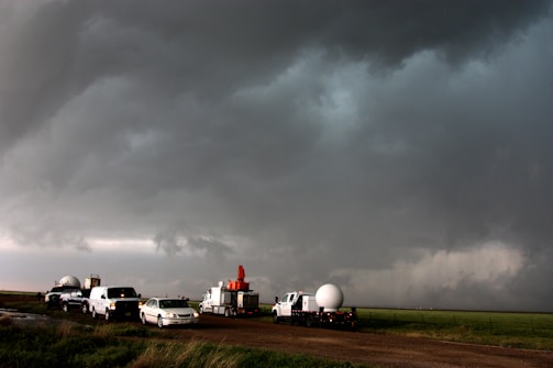 Technicians installing GPS devices on a fleet of trucks in a farm environment.