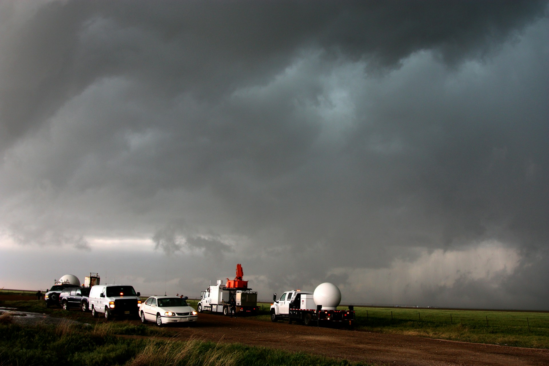 A convoy of second-hand vehicles packed and ready to depart from Silverstone, with volunteers loading supplies under a cloudy sky.