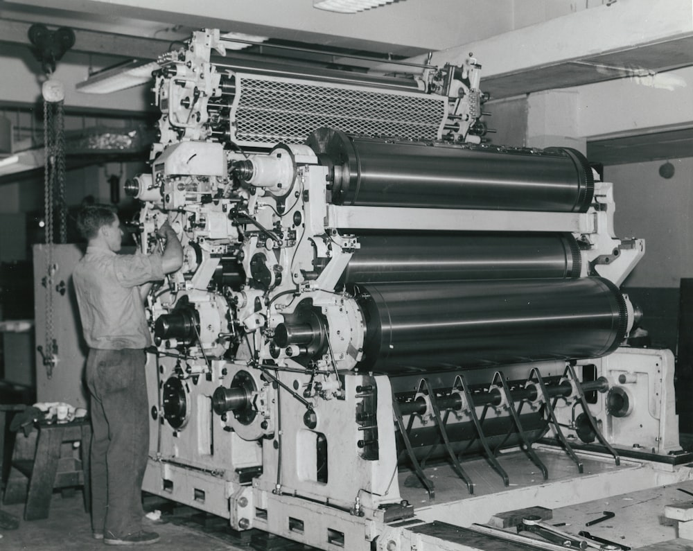 man in white shirt standing beside green machine