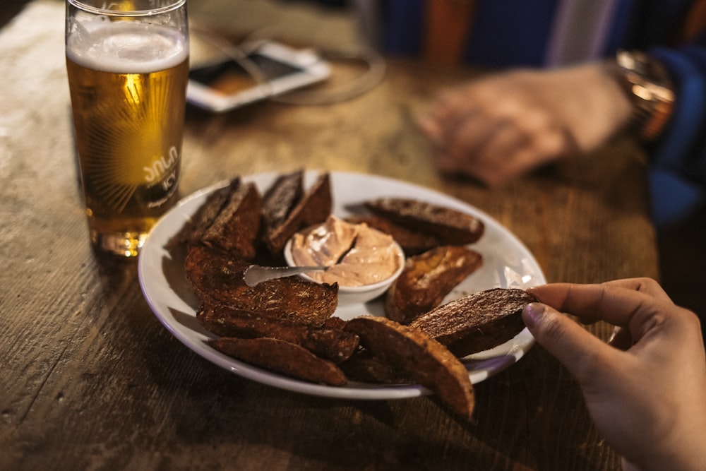 sliced meat on white ceramic plate beside clear drinking glass