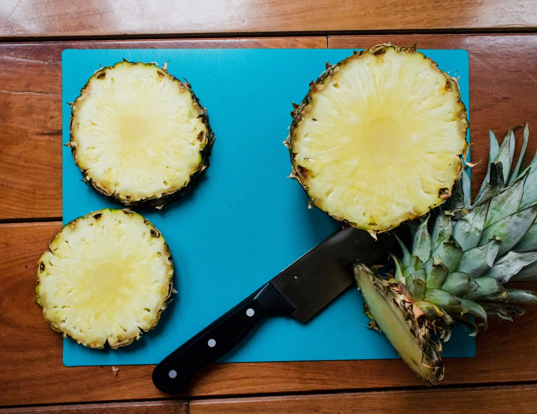 sliced pineapple fruit beside black handled knife