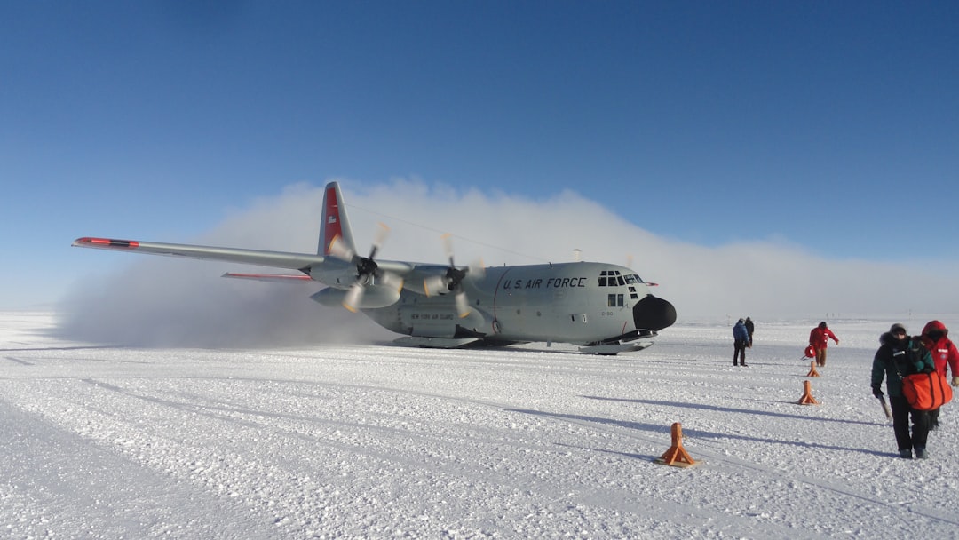 white and red airplane on white snow field during daytime