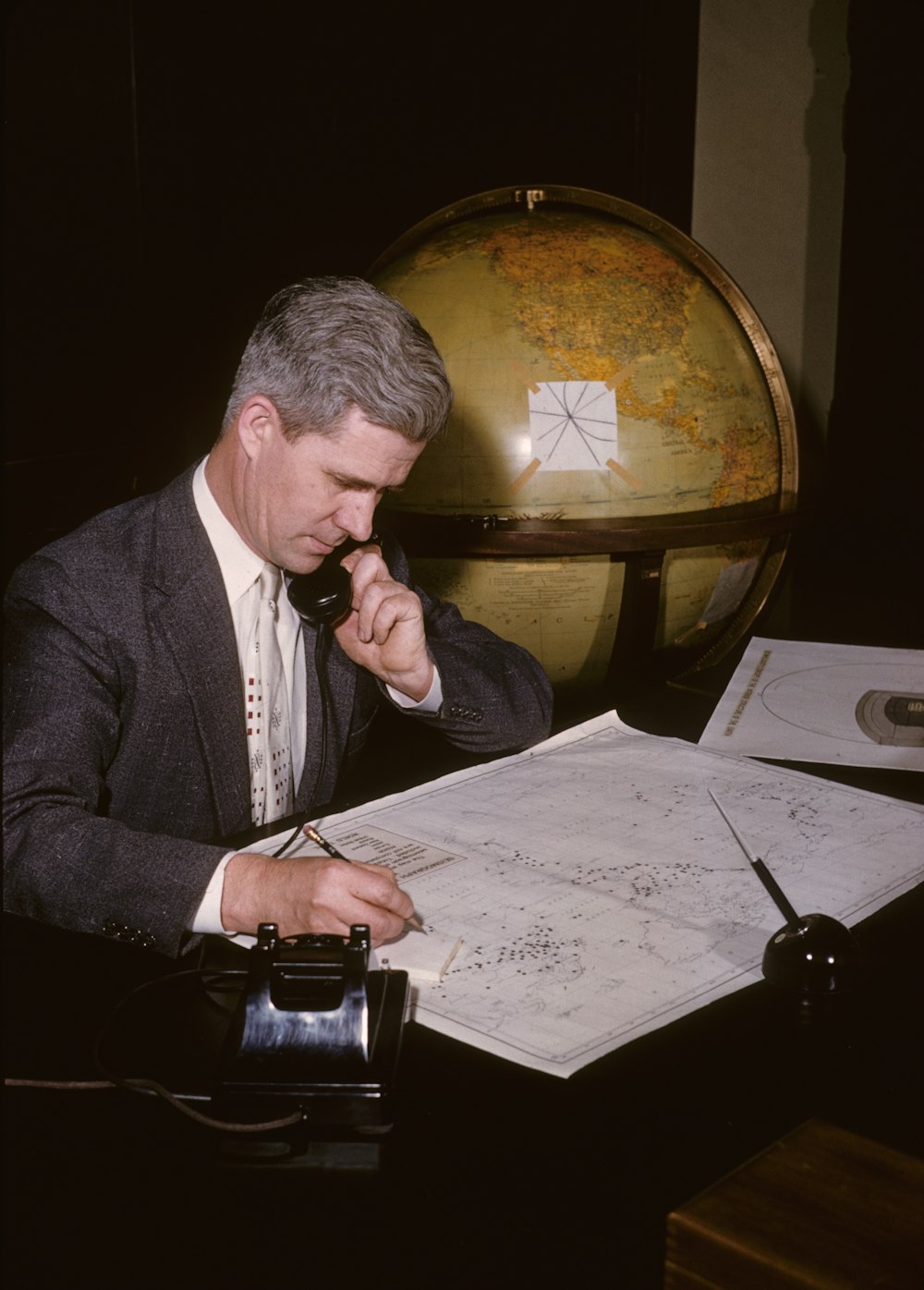 man in black suit jacket writing on white paper