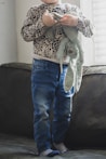 person in blue denim jeans and brown and white leopard print coat standing on black textile