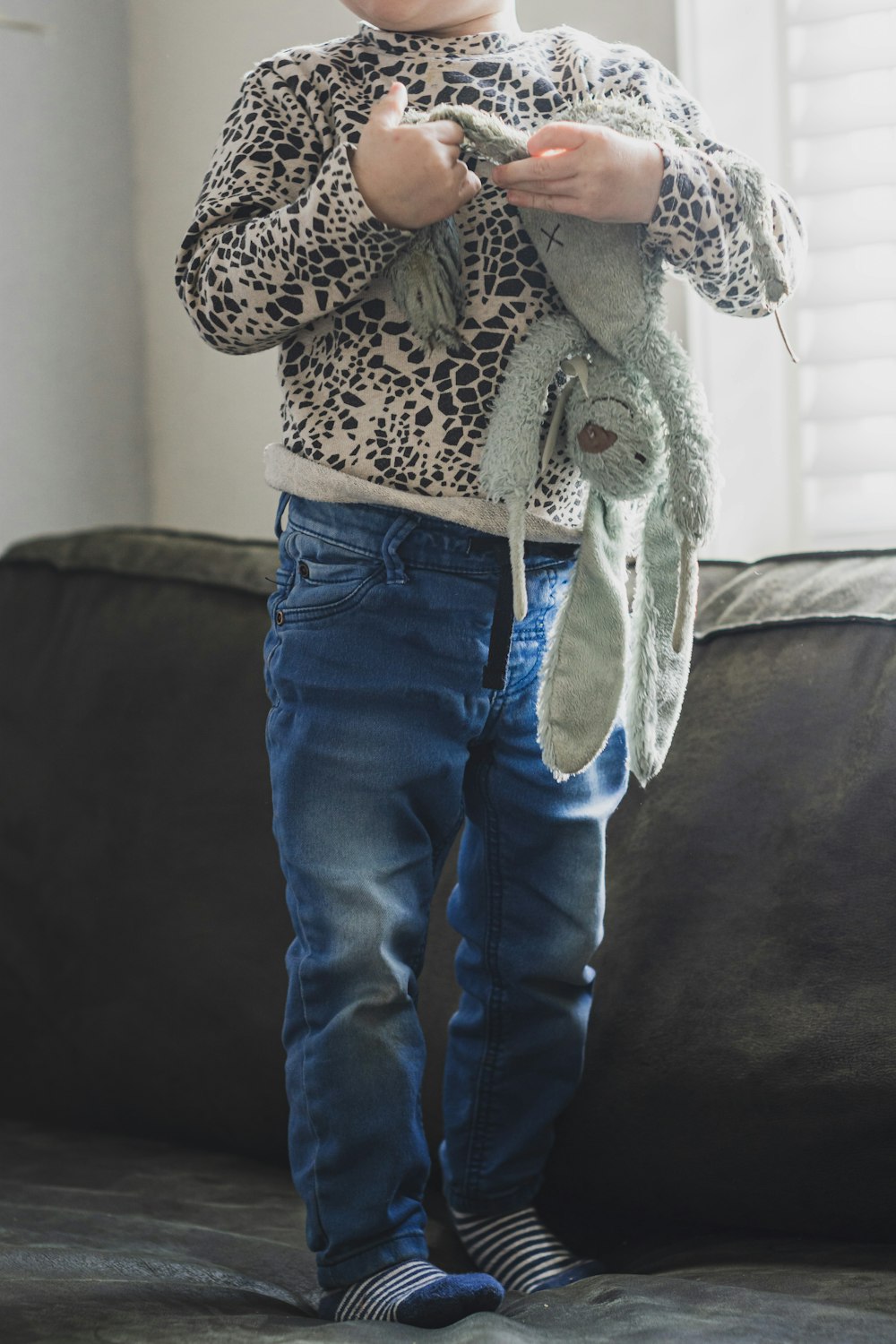 person in blue denim jeans and brown and white leopard print coat standing on black textile